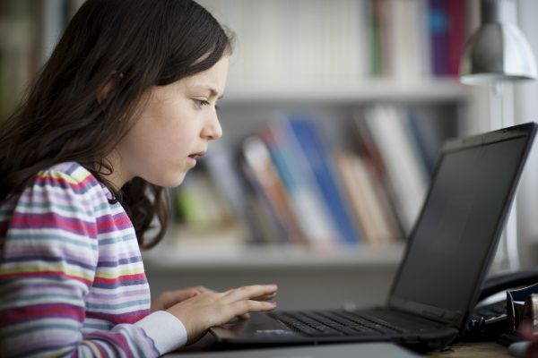 Nine year old girl playing on laptop