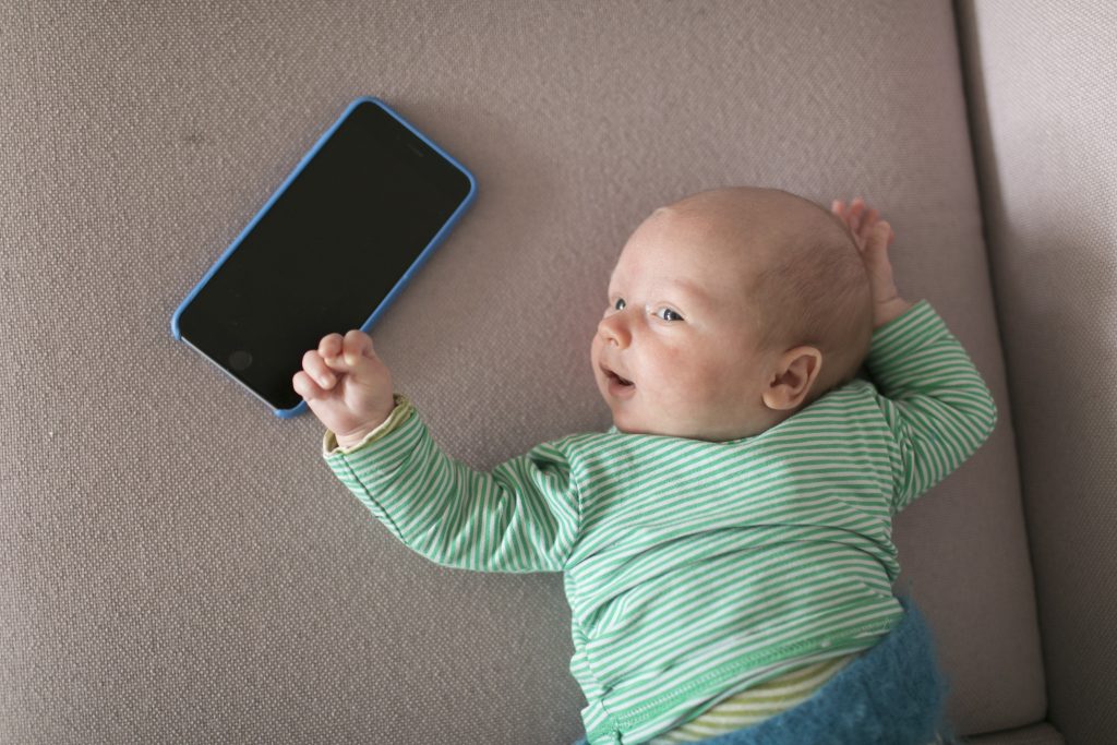 Liegendes Baby mit Smartphone