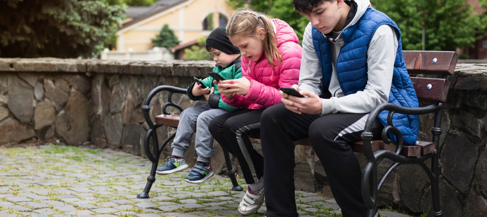 Kinder und Jugendliche mit Smartphone auf Parkbank © Marian Fil/Shutterstock.com